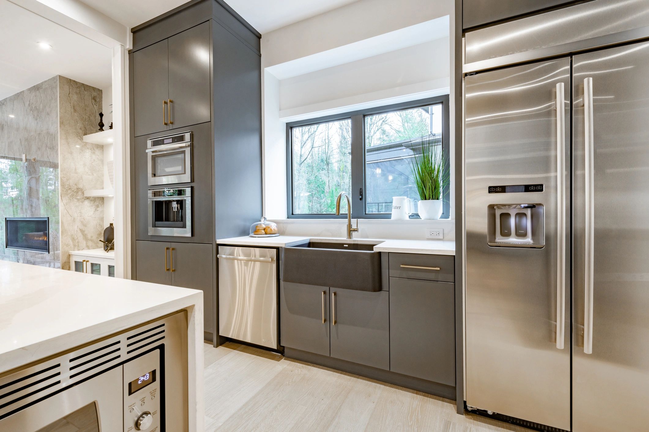 Modern kitchen with gray cabinets, stainless steel appliances, and a large window above the sink.