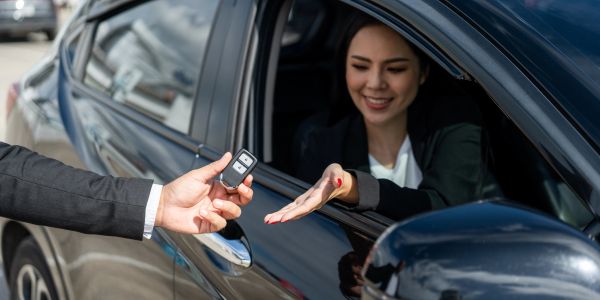 Woman receives car keys from man at car window.