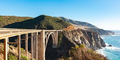 Rugged Pacific coastline with turquoise waves and steep cliffs under blue sky.