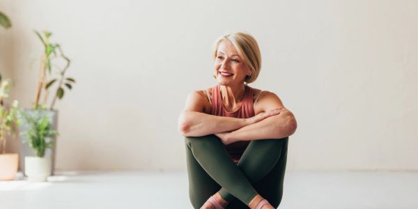 Smiling woman sitting cross-legged indoors.