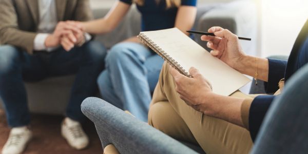 A therapist takes notes during a couple's session.