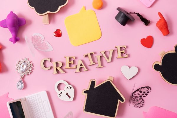 Colorful creative workspace items arranged on a pink background.