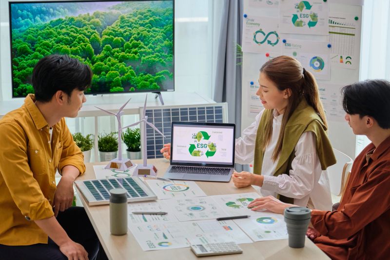 Group of Diversity business people having a ESG meeting environment, society and governance, discussing renewable energy with wind turbine  and solar panel ,eco-friendly  net zero emission clean business  ethical, reduce carbon footprint pollution greenhouse gas, reuse and recycle for sustainable Development goals