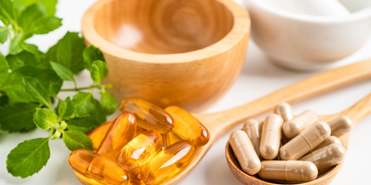 Herbal supplements and capsules on wooden spoons.