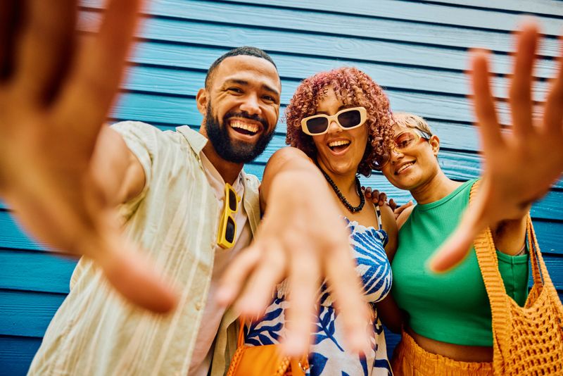 Happy, diverse group of friends posing in front of a beach hut on vacation.