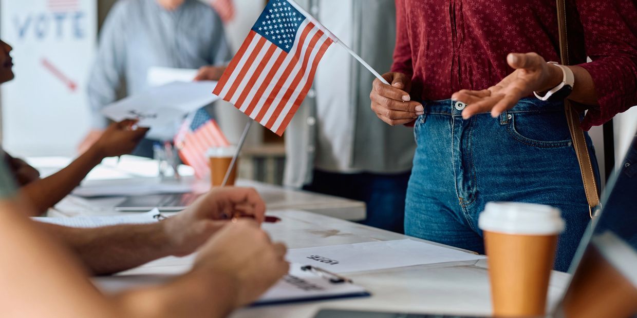 Person holding American flag at a voting station.