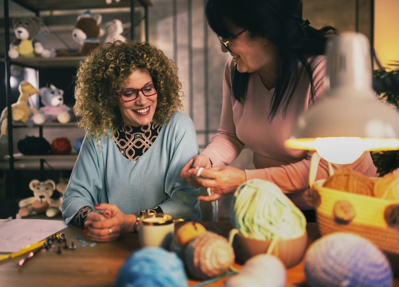 senior woman helps her daughter with knitting