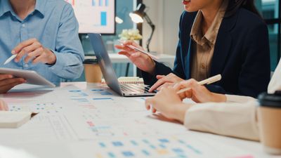 Team discussing data charts and graphs at a meeting table.