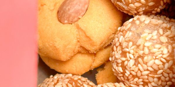 Close-up of almond cookie and sesame-coated sweets in a box.