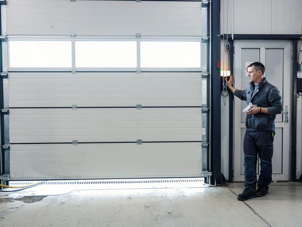 A man operating a garage door in an industrial setting.