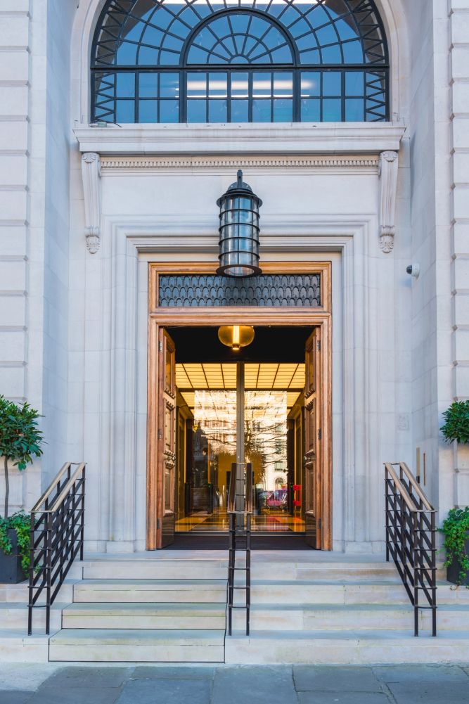 Elegant entrance with wooden doors and glass panels on stone steps.
