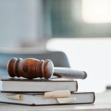 Wooden gavel resting on a stack of legal books.