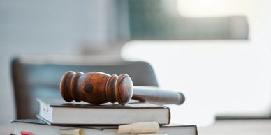 Wooden gavel resting on legal books on a table.