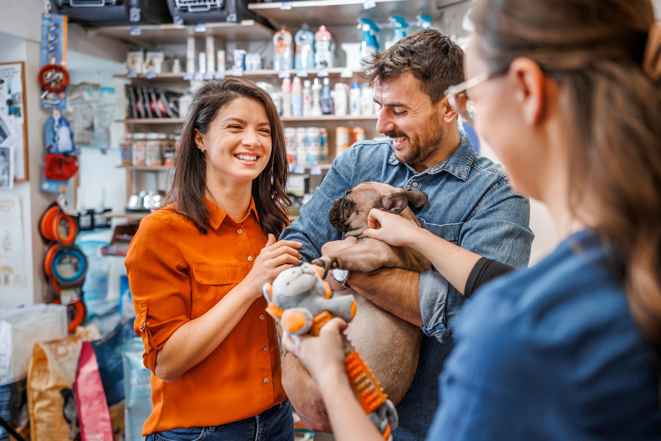Happy couple with their dog at a pet store, smiling and playing.