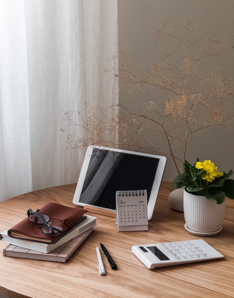 Home office - tablet, books, notebooks, calendar, calculator and home flower on a wooden table
