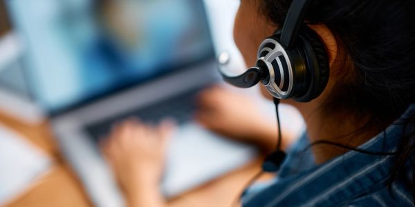 Person wearing headset using laptop for communication.