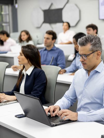 Adults attending a classroom session using laptops.