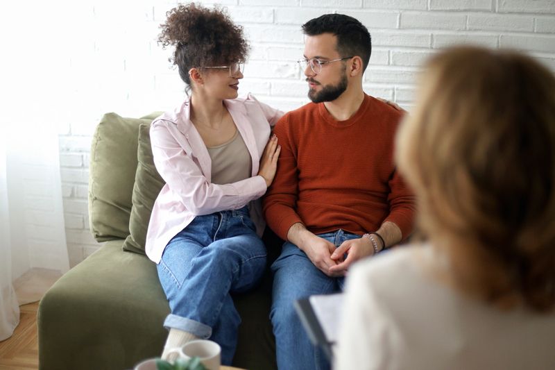 Young couple talking to a psychiatrist during a counseling. Both about 25 years old, mixed-race female and Caucasian male.