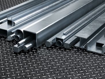 Various metal bars and rods arranged on a textured metal surface.