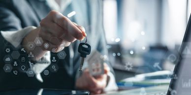 Businessperson holding a house key in an office setting.