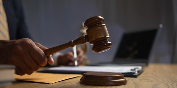 Judge's hand holding a wooden gavel in a courtroom setting.