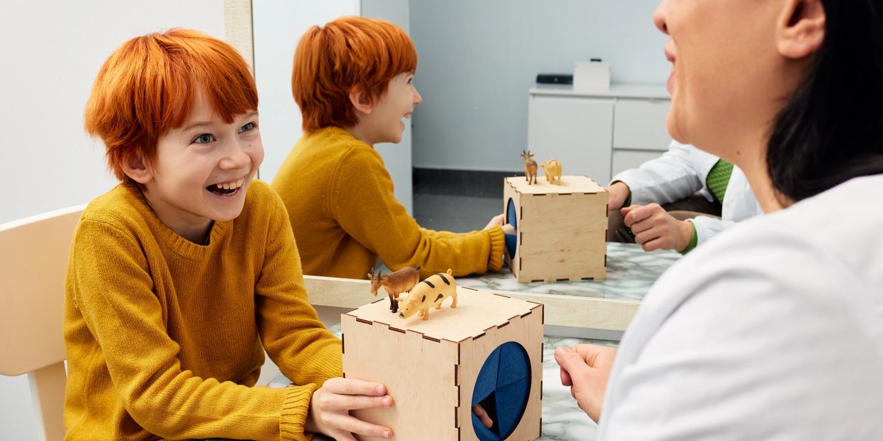 A joyful child and adult engage with a wooden sensory toy at a table.