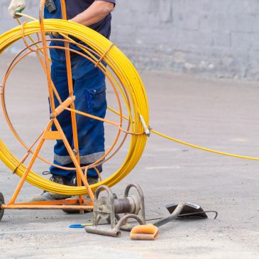 Worker handling yellow cable reel outdoors.