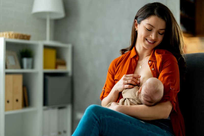 Happy mother breastfeeding and hugging newborn baby.
