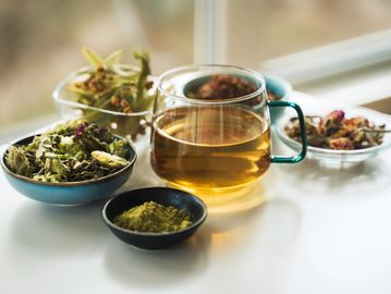 Taza de té con hierbas y especias secas alrededor.