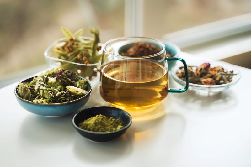 A cup of tea with dry fruit, flowers, and herbs.