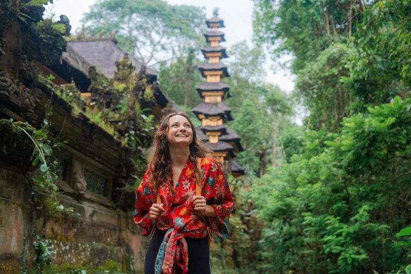 Woman walking past the temple in the jungles in Ubud, Bali