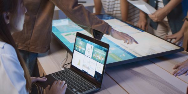 Group collaborating with laptop and interactive touchscreen table.