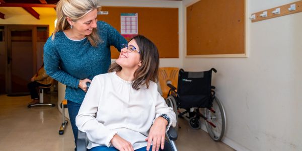 Woman in wheelchair smiling at her caregiver.