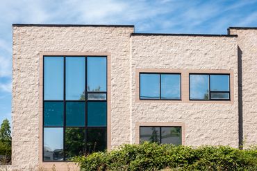 Modern building facade with large rectangular windows and a beige brick exterior.