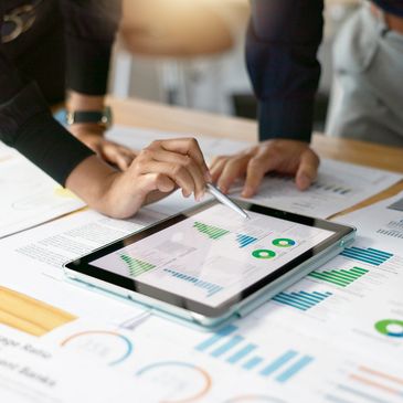 People analyzing financial charts and data on tablet and papers.