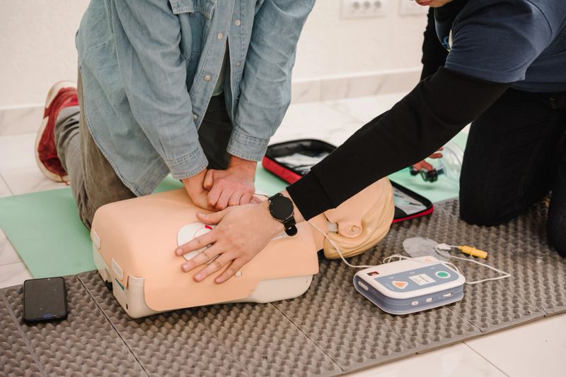 Demonstrating chest compressions. Automated external defibrillator device, AED with training dummy mannequin. Use an automatic defibrillator in conducting basic cardiopulmonary resuscitation of victim