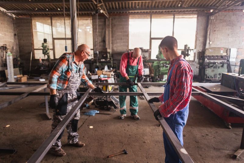In the bustling metal workshop, a group of individuals diligently assemble a large metal structure.