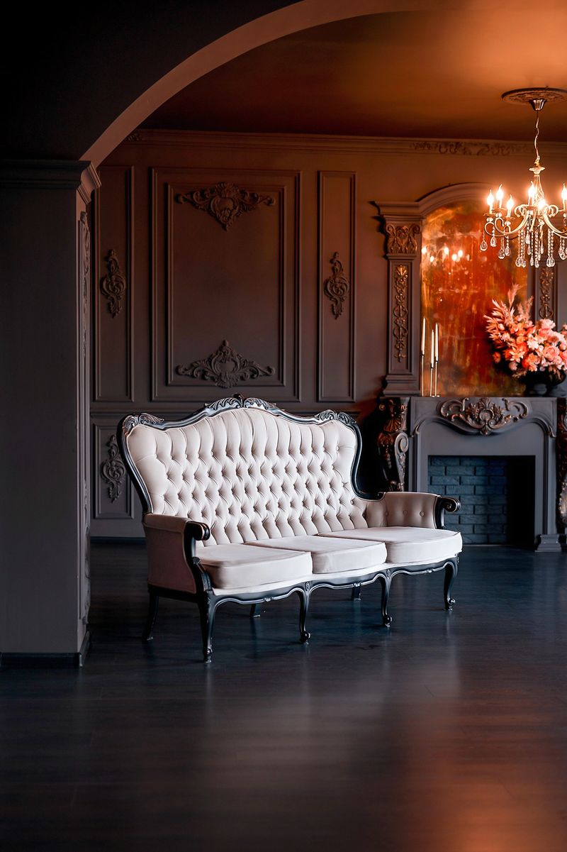 Black classical room interior with a vintage sofa, chandelier, mirror and fireplace decorated with flowers