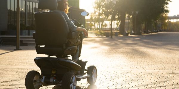 Woman enjoying a sunny afternoon on a mobility scooter outdoors.