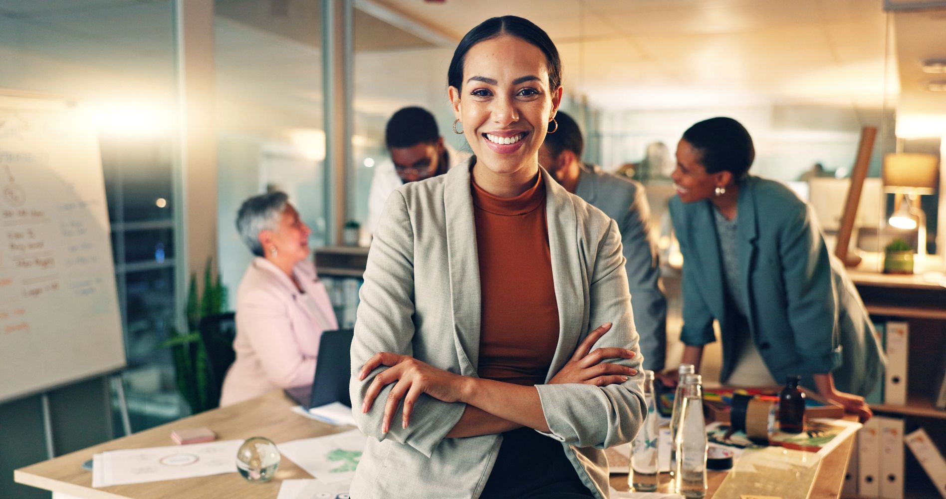 group of people learning in a classroom with a woman of color sitting at a table teaching

