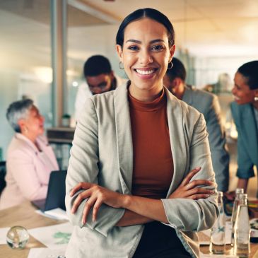 Confident businesswoman smiling in office with colleagues.