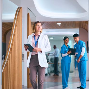 Female doctor holding a tablet, smiling in a hospital corridor.