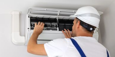 Technician fixing an air conditioner indoors.