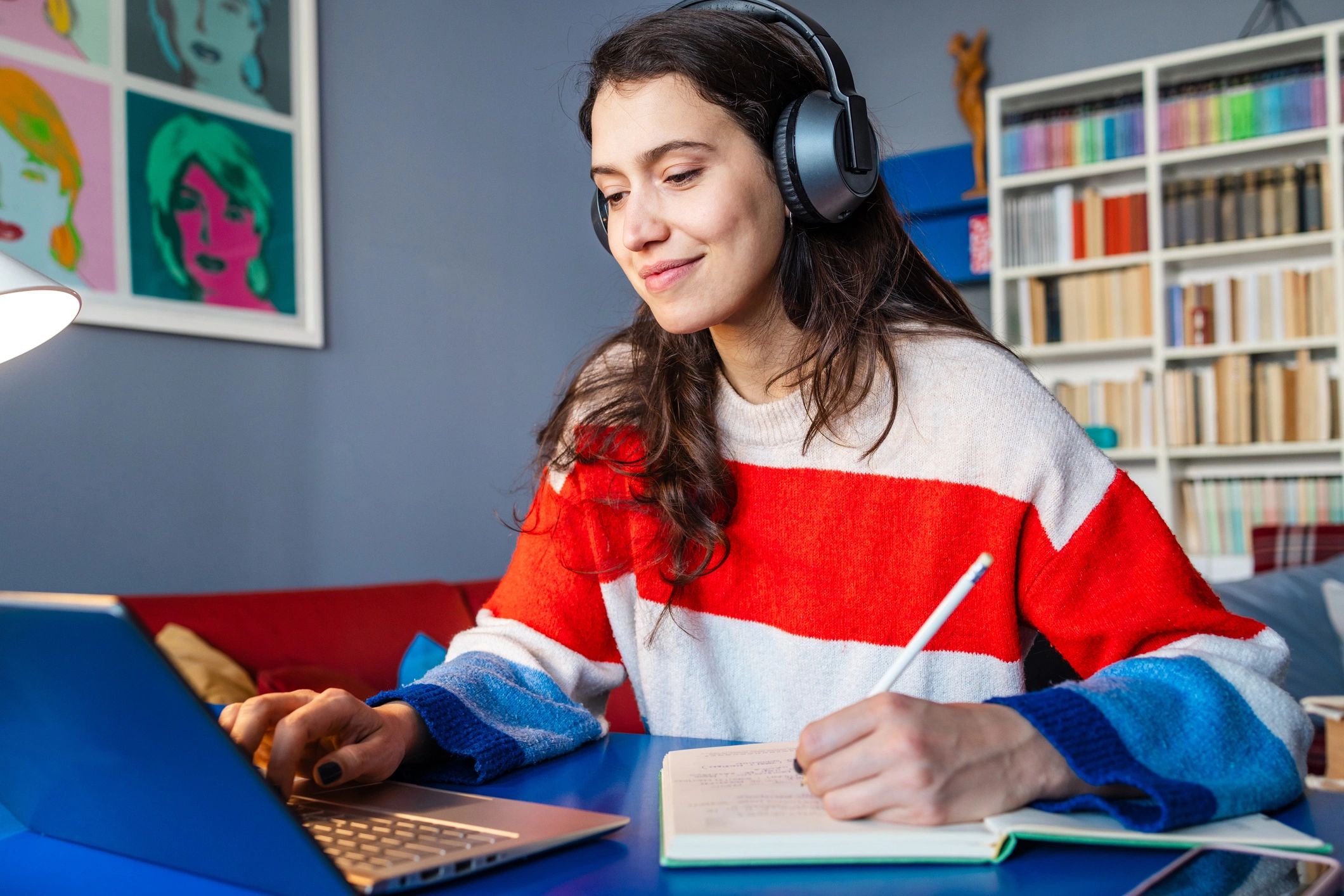 Young woman studying with headphones and laptop.