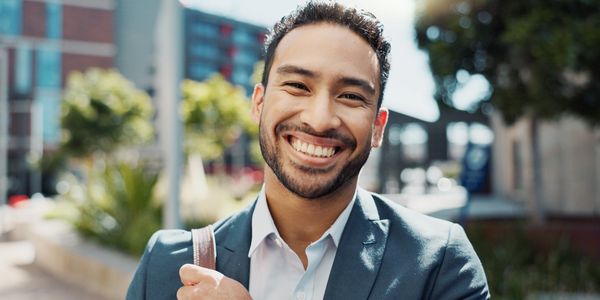 Smiling young man in a suit outdoors, looking confident and happy.