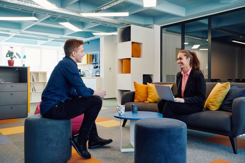 Multiethnic startup business team on meeting in a modern bright open space coworking office. Brainstorming, working on laptop. Group of coworkers walking around in motion blur.