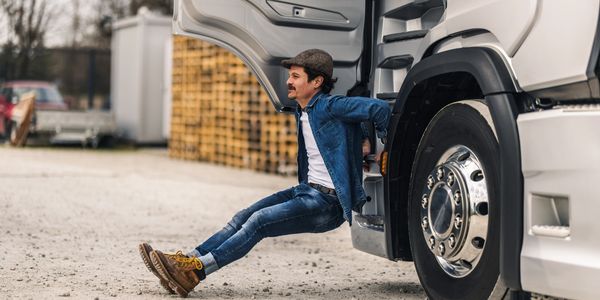 Man doing tricep dips using a truck's side handle outdoors.
