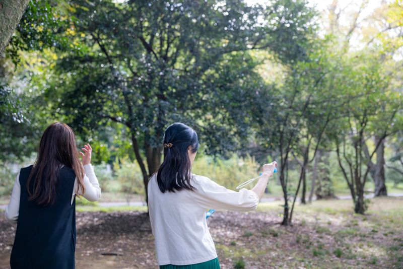 Rear view of female friends playing with soap bubbles in public park