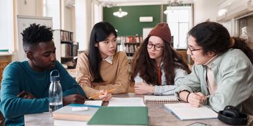 Four diverse students studying together in a library.