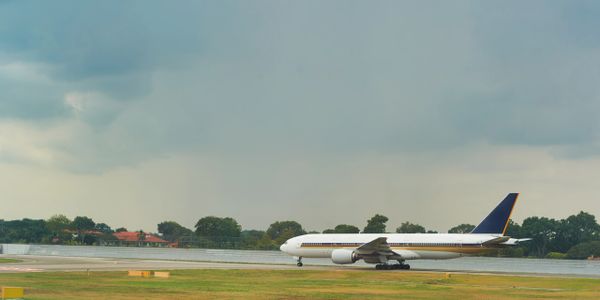 Commercial airplane taxiing on runway with cloudy sky.